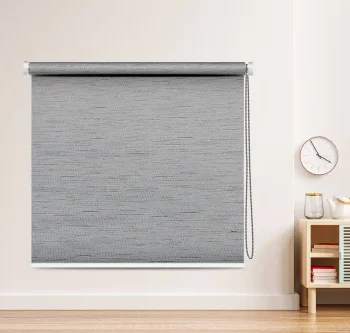 Textured gray blackout roller blind with a chain mechanism in a modern living room setup.