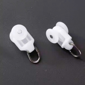 Set of white curtain M track runners with plastic wheels and metal hooks, displayed on a dark surface for detail clarity.